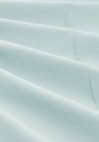 Light blue fabric with a smooth texture, featuring folded layers and subtle stitching detail. The material appears soft and slightly reflective.