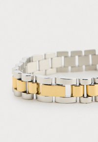 Zilveren en gouden metalen armband met onderling verbonden schakels in rechthoekige en ronde vormen, een gladde textuur en een gepolijste afwerking.