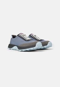 Zapatillas deportivas en textil azul y gris con suela de goma de contraste, cordones blancos y detalles texturizados en la suela.