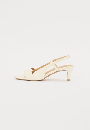 Beige slingback heel with a slight pointed toe and three horizontal straps across the front. Features a mid-height heel and smooth texture.