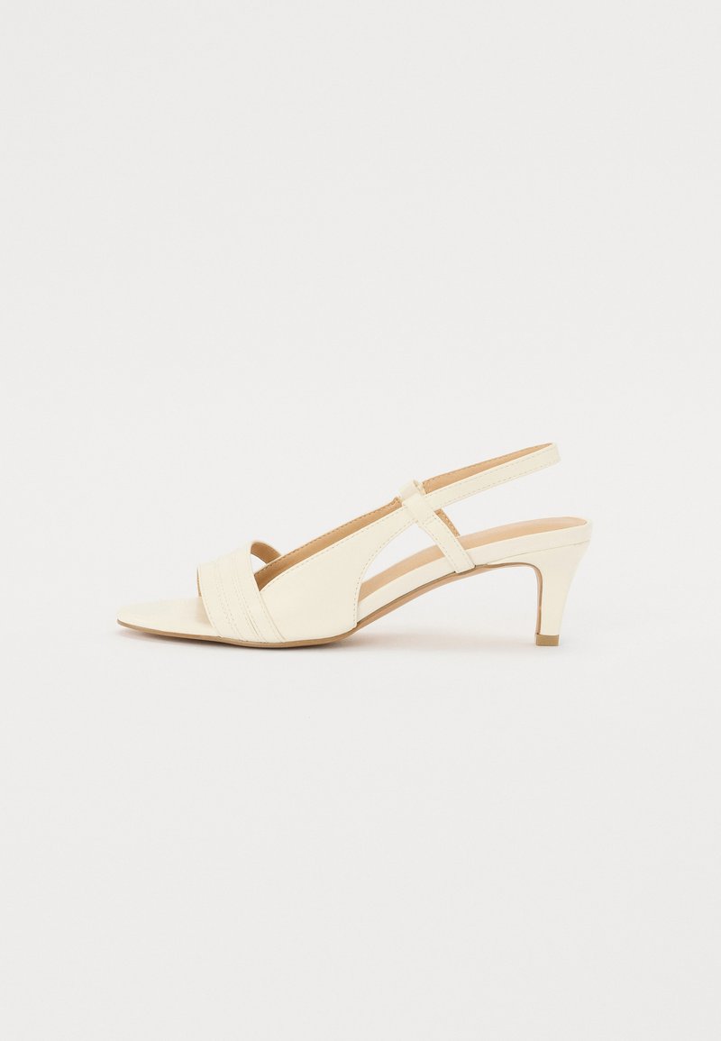Tacchi slingback beige con punta leggermente appuntita e tre strisce orizzontali nella parte anteriore. Caratterizzati da un tacco di altezza media e da una superficie liscia.