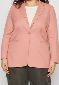 Pink blazer made of lightweight fabric, featuring a single button closure, notched lapels, and side pockets. Subtle logo on the chest.