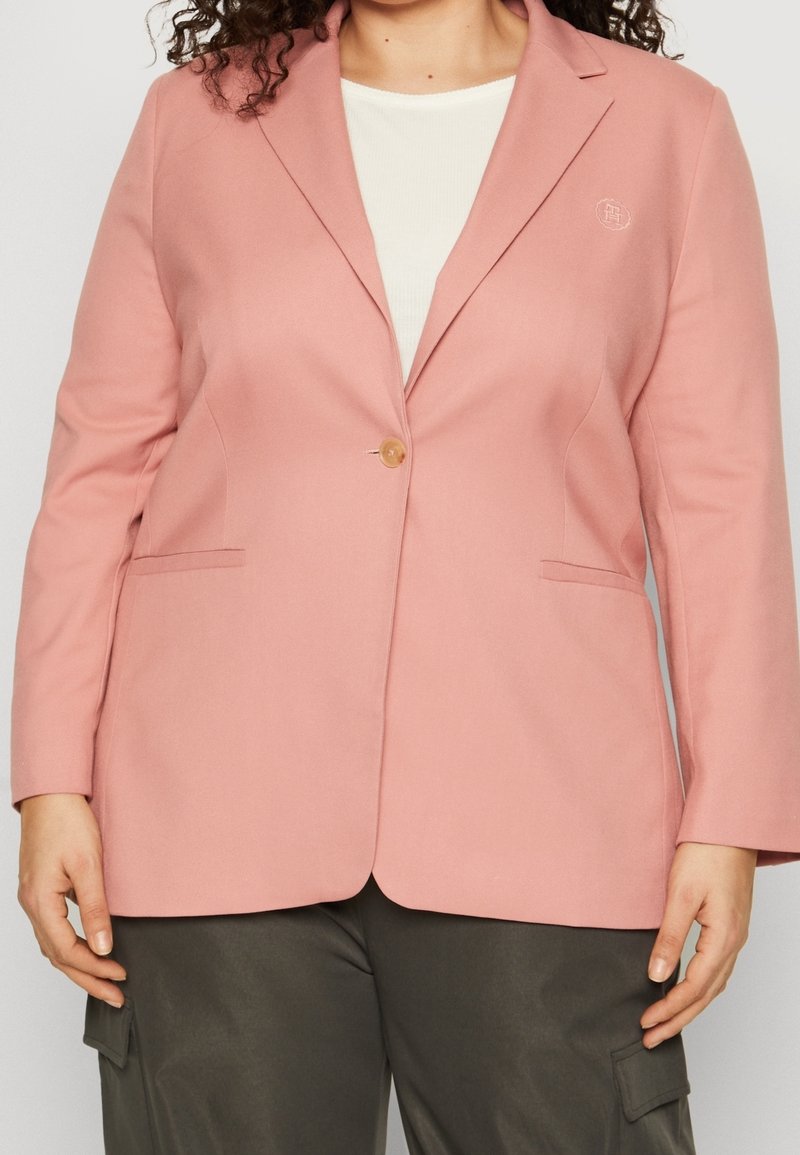 Pink blazer made of lightweight fabric, featuring a single button closure, notched lapels, and side pockets. Subtle logo on the chest.