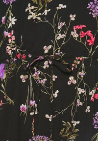 Svart tyg med blommönster i lila, rosa och vitt. Har en dragsko i midjan för justering. Slät textur.