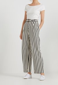 Czarno-białe spodenki w paski o szerokich nogawkach, z wysokim stanem i detalem paska. W połączeniu z dopasowaną białą bluzką z krótkim rękawem.