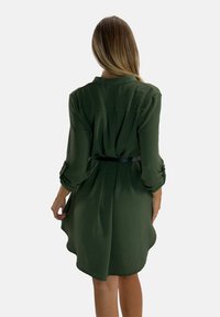 Abito verde con una vestibilità rilassata, maniche lunghe e vita cin cin. Realizzato in tessuto leggero con una superficie leggermente strutturata.