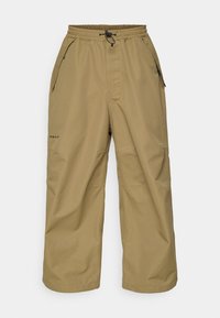 Khaki cargo bukser laget av vannavvisende stoff, med elastisk midje, snøring og flere glidelåslommer.