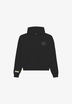 Mustmust jaes ees kõhukott, väikese omavahel seotud ringikujulise logoga rinnal ja beeži ristkülikukujulise lapiga vasakul varrukal.