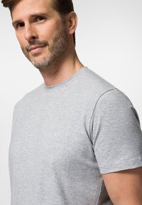 Szara koszulka z krótkim rękawem i okrągłym dekoltem, wykonana z miękkiego, teksturowanego materiału. Posiada wytłoczone logo na klatce piersiowej.