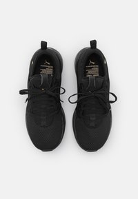 Chaussures de sport noires avec une tige en maille, des lacets plats, une semelle rembourrée et des accents dorés minimalistes. Design léger et contemporain.