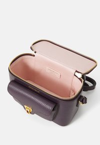 Purple leather bag with gold hardware, zip closure, and a pebbled texture. Interior features a light pink lining and brand label.
