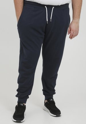 Navy Jogginghosen aus weichem Baumwollmix, mit elastischem Bund, Kordelzug und schmalen Beinen. Mit Seitentaschen gestaltet und mit schwarzen Sneakers kombiniert.