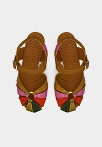 Πολύχρωμα σανδάλια με πολλαπλούς ιμάντες σε τμήματα ροζ, πορτοκαλί, πράσινου και κίτρινου, με μεταλλική λεπτομέρεια και υφασμένο καφέ πέλμα.