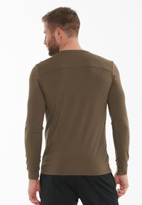Langærmet skjorte i olivengrønt stof, figursyet design med flad sømdetalje over skuldrene, glat tekstur og ingen synlige mønstre.