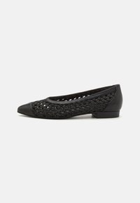 Chaussure plate noire avec une tige en maille tissée et un embout noir uni. Comprend un petit talon bloc et des accents en cuir lisse.