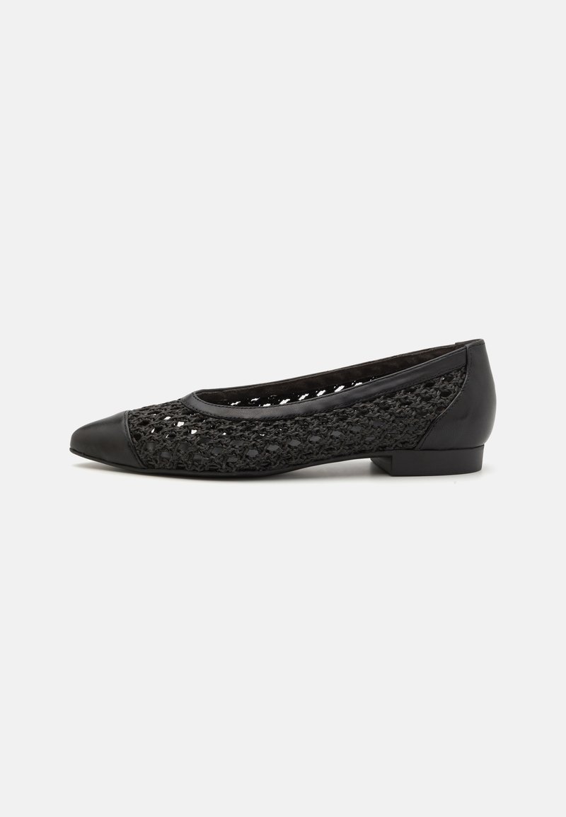 Chaussure plate noire avec une tige en maille tissée et un embout noir uni. Comprend un petit talon bloc et des accents en cuir lisse.