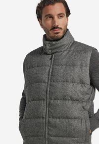 Graue gesteppte Weste mit hohem Kragen, ausgestattet mit Frontreißverschluss und Druckknöpfen. Strukturierter Stoff mit horizontaler Steppung.