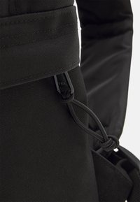 Zaino in tessuto nero in primo piano, presenta materiale testurizzato, cinghie regolabili e componenti neri per durata e funzionalità.