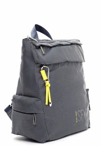 Mochila marina hecha de tejido texturizado con lunares blancos. Cuenta con un zipper en la parte superior, un bolsillo delantero con solapa y un tirador de acento amarillo.