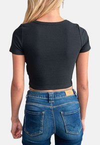 Top court noir à côtes avec des manches courtes, associé à un jean en denim bleu taille haute avec deux poches arrière et des coutures contrastées.