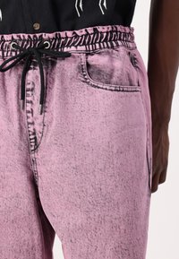Rosa denim joggers med en teksturert finish, med elastisk midjebånd og snøring, sidelommer og subtile svarte detaljer.