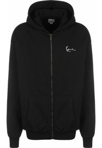 Zwarte zip-up hoodie gemaakt van een zacht materiaal, met een voorzak, ribgebreide mouwen en een klein wit logo op de linkerborst.