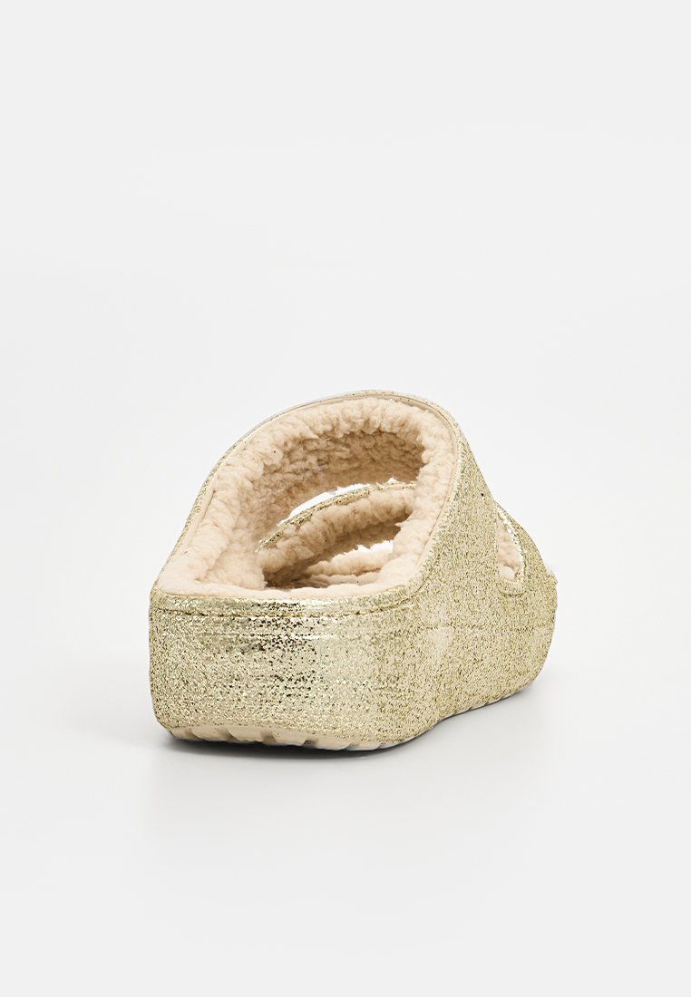 Gouden glitter instap-slof met een pluche, beige nep-bonten voering. Kenmerkt zich door een ronde vorm en een open achterkant ontwerp voor gemakkelijk aan- en uittrekken.