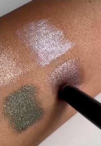 Three swatches of eyeshadow applied to skin: top left silvery shimmer, top right pink shimmer, bottom left olive green with a textured finish.