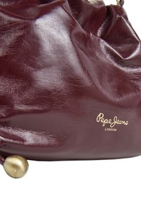 Borsa in finta pelle borgogna con una texture stropicciata, caratterizzata da un logo dorato, hardware in ottone arrotondato e un design morbido.