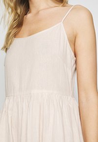 Jasnoliliowa sukienka bez rękawów z cienkimi ramiączkami, dopasowanym gorsetem i zwiewną spódnicą z marszczeniem w talii.