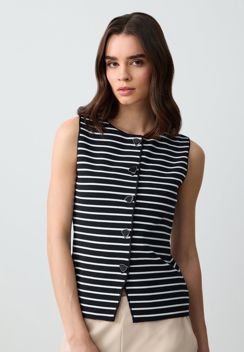 Ärmelloses Oberteil mit schwarz-weißen Streifen, rundem Halsausschnitt und Knopfverschluss, mit einem Schlitz am Saum für einen maßgeschneiderten Look.