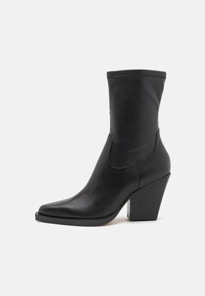 Botine negre din piele, cu vârf ascuțit, panouri laterale elastice și toc gros, înalt. Textură netedă și design elegant.