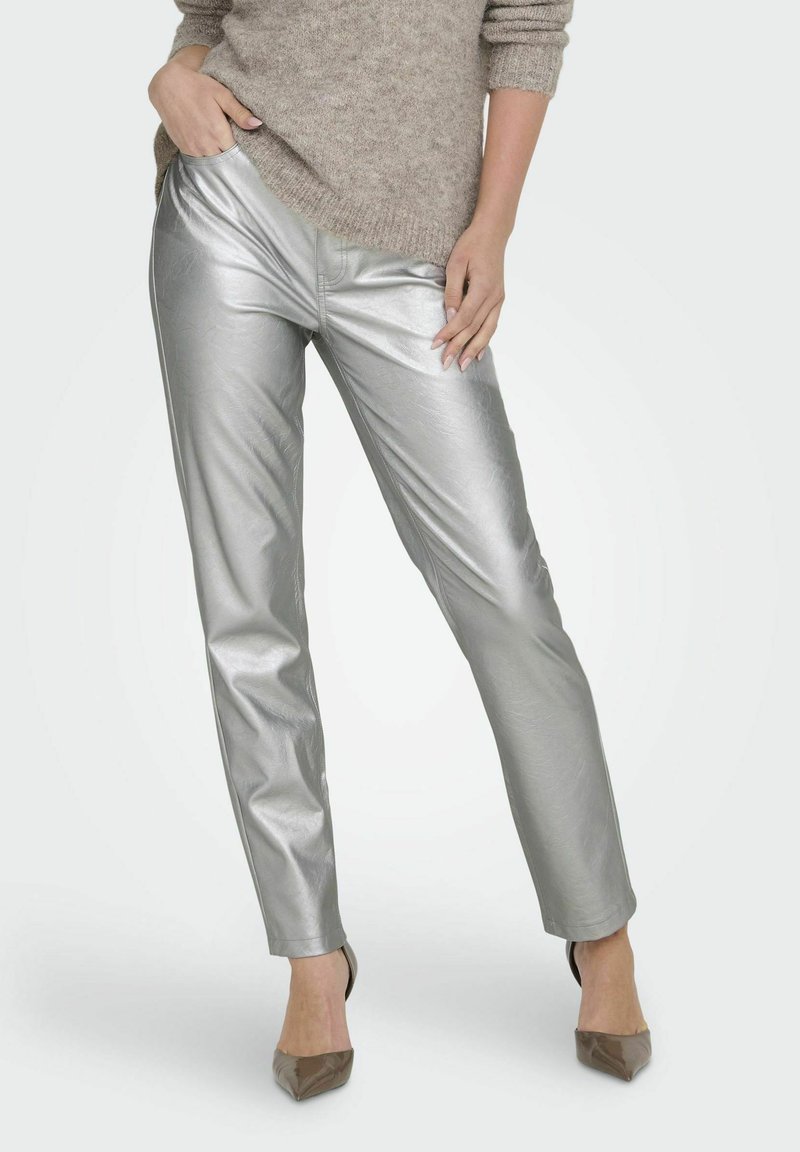 Zilveren metallic slim-fit broek met een gladde textuur en subtiele kreukels. Draag het met een lichtbruine gebreide trui en puntige hakken.