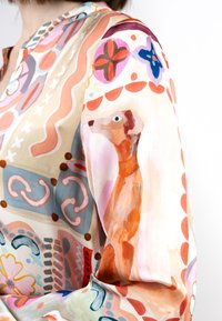 Bunte Bluse aus leichtem Stoff mit abstrakten Mustern in Rosa, Orange und Blau, akzentuiert durch ein Gemälde eines Greyhounds auf dem Ärmel.