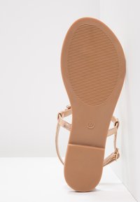 Light tan sandal with a textured rubber sole, adjustable straps, and a metallic sheen. Size 37 marked on the sole.
