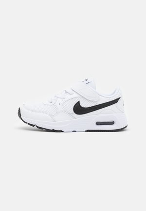 Hvid atletisk sneaker med sort Nike swoosh, mesh paneler, velcro-rem og synlig air cushion sål, set fra siden.