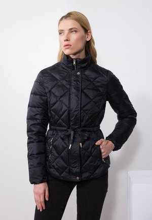 Veste en duvet noire matelassée avec un col haut, une taille à cordon et des poches latérales zippées. Présente des accents en métal doré.