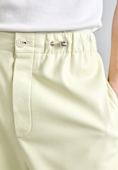 Helle gelbe Kunstlederhosen mit elastischem Bund, Knopfverschluss und seitlichen Taschen. Glatte Textur und dezenter Glanz.