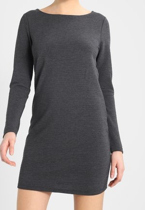 Female wearing a fitted, long-sleeve, dark gray ribbed knit dress with a boat neckline, standing against a plain background.
