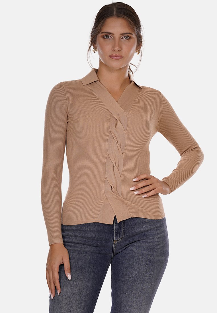 Maglione di maglia a coste beige con scollo a V, dettaglio frontale a torsione e maniche lunghe, abbinato a jeans scuri. Texture morbida e design aderente.