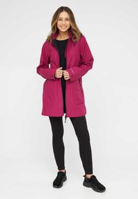 Chaqueta magenta con cierre de cremallera, bolsillos laterales dobles, capucha ajustable y mangas largas, combinada con leggins negros y zapatillas negras.