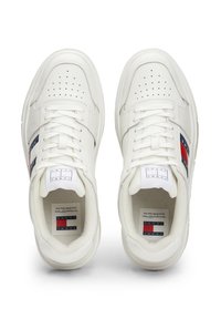 Sneaker in pelle bianca con punta perforata, lacci piatti e strisce laterali blu/rosse. Presenta loghi sulla linguetta e sulle sole interne. Suola in gomma.