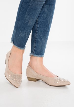 Beżowe zamszowe baleriny z szpiczastym noskiem i niskim obcasem, ozdobione grupą srebrnych ćwieków na przedniej części buta. Noszone z postrzępionymi dżinsami.