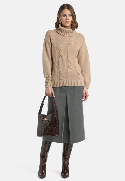 Pulover bej din tricot cu modele în cable, guler înalt și tiv striat, asortat cu o fustă gri și o geantă din piele cu model de crocodil, maro.