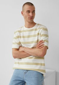 Witte short-sleeve t-shirt met gele horizontale strepen, relaxte pasvorm, ronde halslijn, textiele stof, gecombineerd met lichtblauwe jeans.