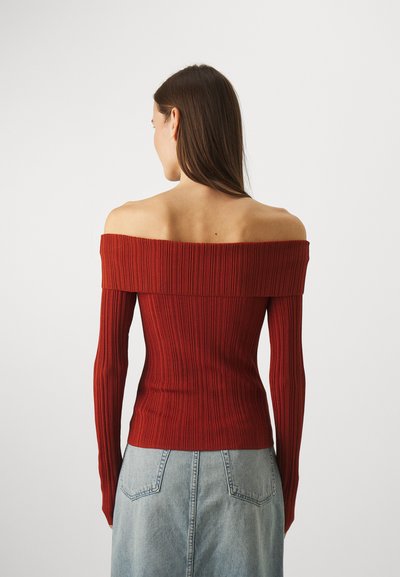 Ribbed, off-shoulder sweater in deep red, featuring long sleeves and a fitted design. Back view shows a smooth transition to the lower garment.