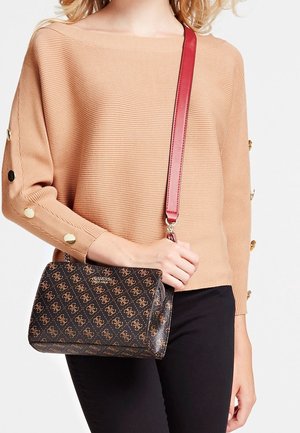 Beżowy sweter w prążki z złotymi guzikami i bordowa torba na ramię z powtarzającym się wzorem logo. Czarne spodnie dopełniają stylizację.
