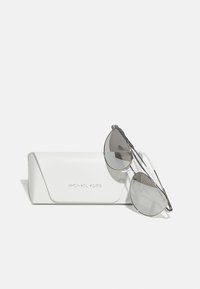 Óculos de sol com armação metálica prateada e lentes cinzas espelhadas, repousando sobre um estojo rígido texturizado branco com o logótipo da marca em relevo.