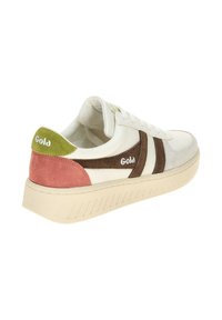 Baskets blanches avec des accents marron et vert, dotées d'un talon en daim rose, d'un matériau texturé, d'un système de laçage et d'une semelle en caoutchouc striée.