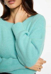 Maglione lavorato a maglia blu chiaro con texture a coste e scollatura ampia. Presenta maniche ampie e un materiale morbido, che offre una vestibilità comoda.